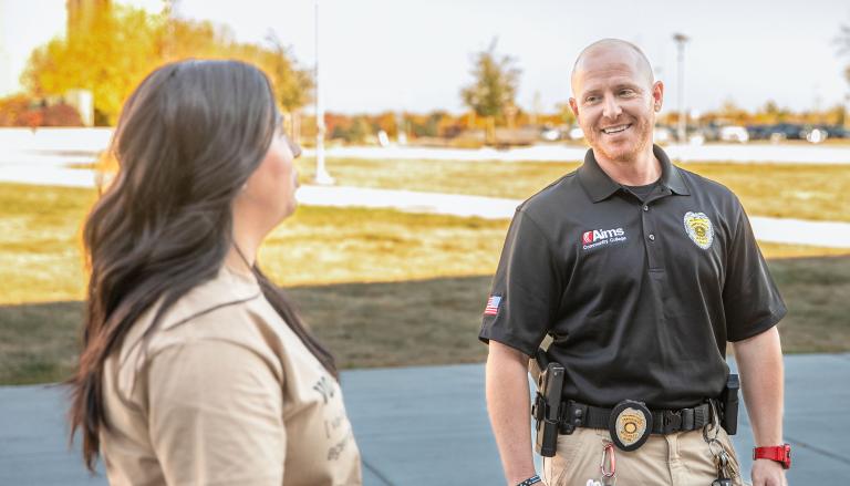 An Aims Community College Safety and Security Officer smiles while talking with a student on the Greeley Campus.